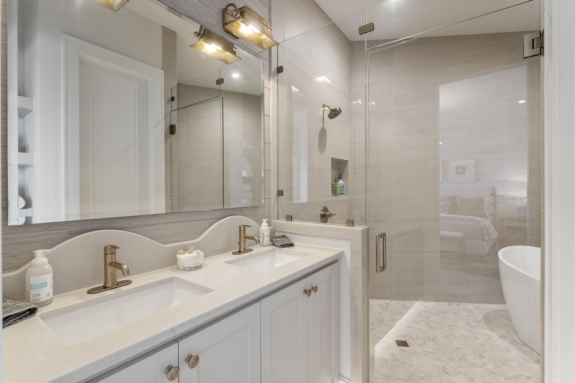 A bathroom with a sink , mirror and walk in shower.