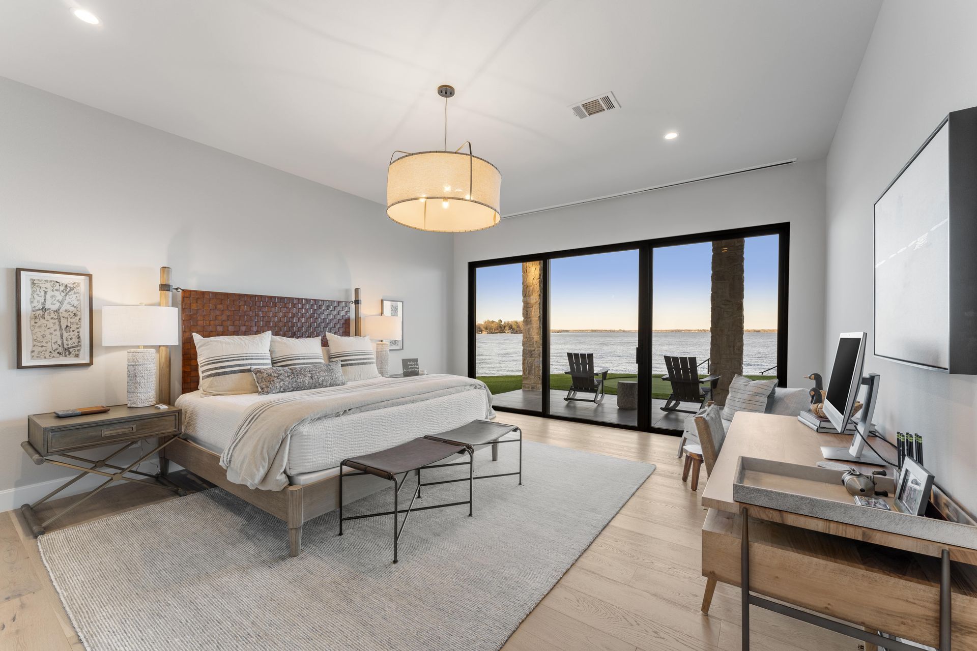 A bedroom with a large bed and a desk with a view of the ocean.