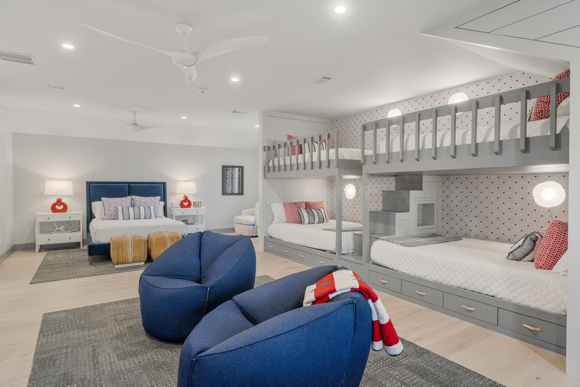 A bedroom with bunk beds , chairs , and a couch.