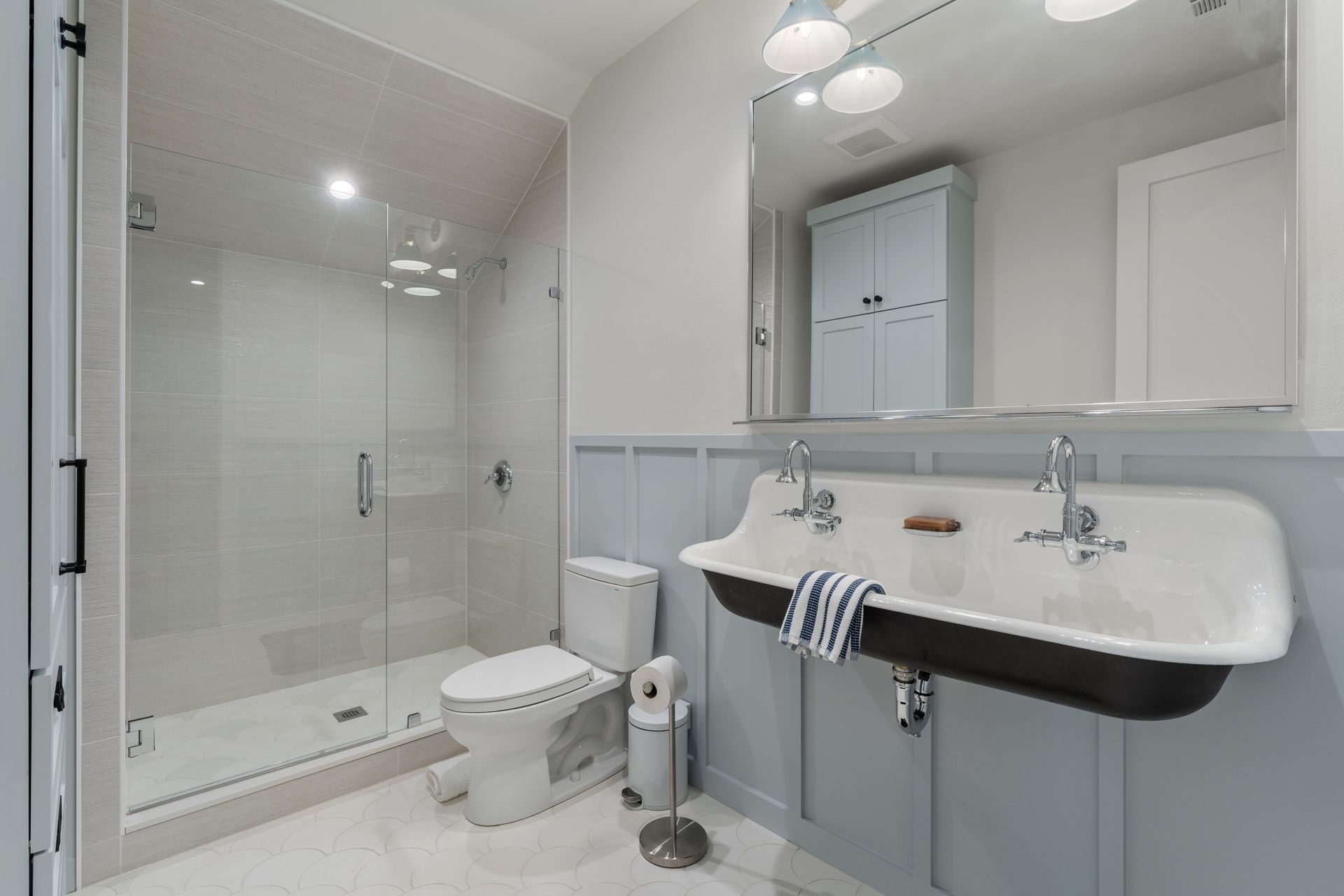 A bathroom with a sink , toilet , shower and mirror.