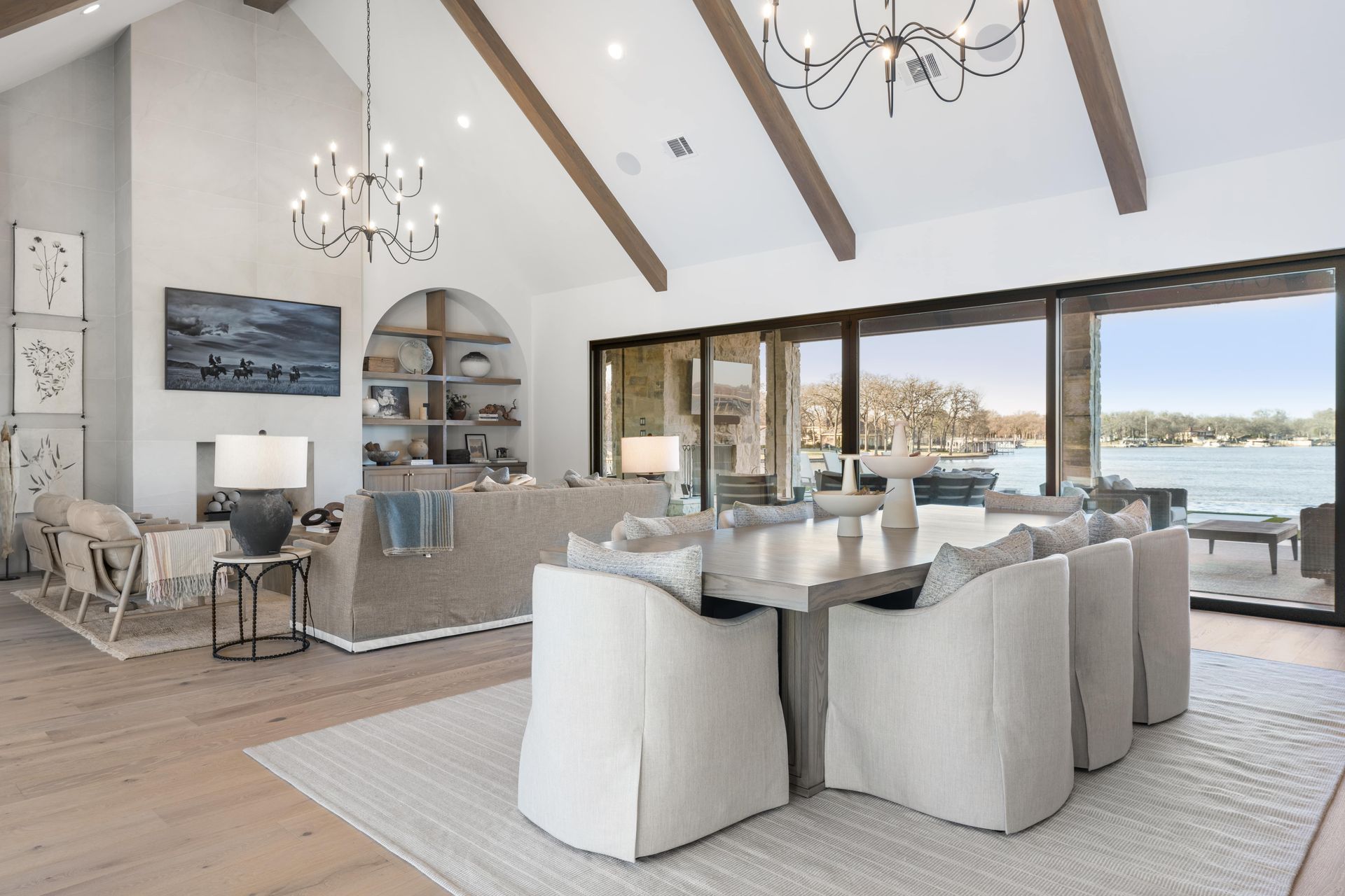 A living room with a table and chairs and a view of a lake.