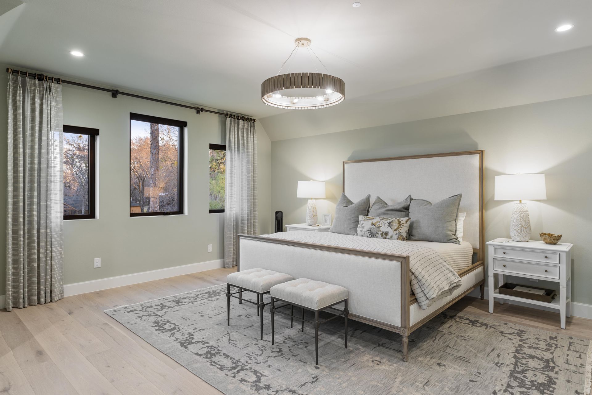 A bedroom with a large bed , nightstands , lamps and a rug.