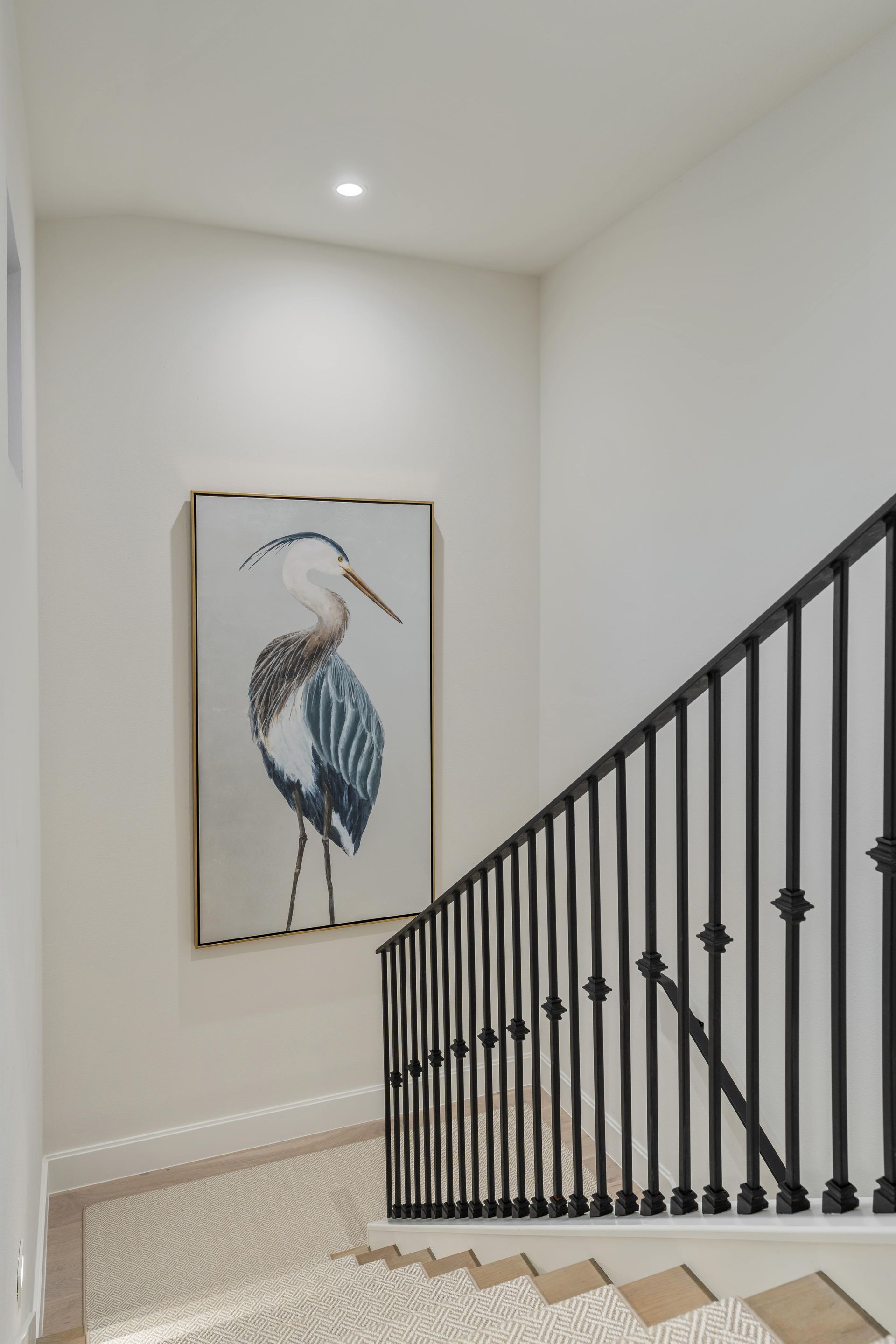 A staircase with a painting of a bird on the wall.