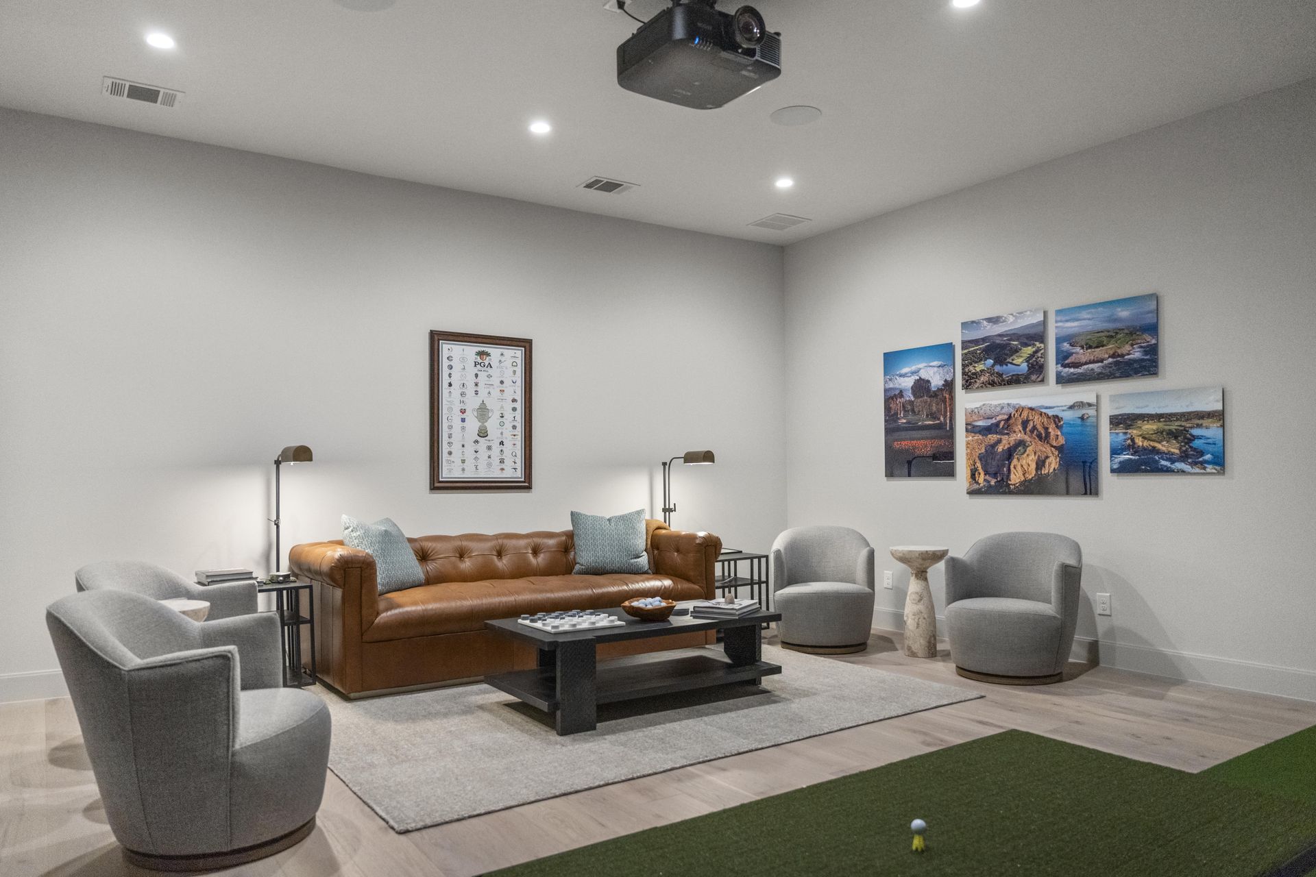 A living room with a couch , chairs , a coffee table and a projector.