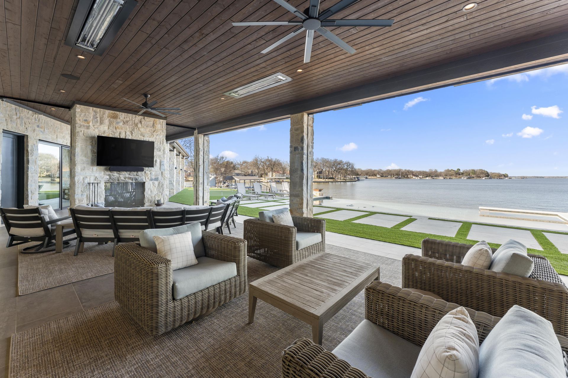 A patio with wicker furniture and a ceiling fan overlooking the water.