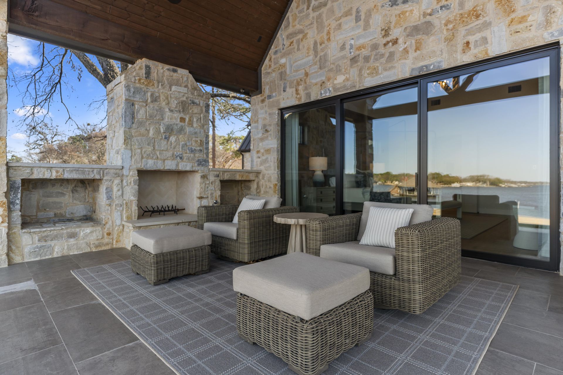 A patio with chairs and ottomans and a fireplace.