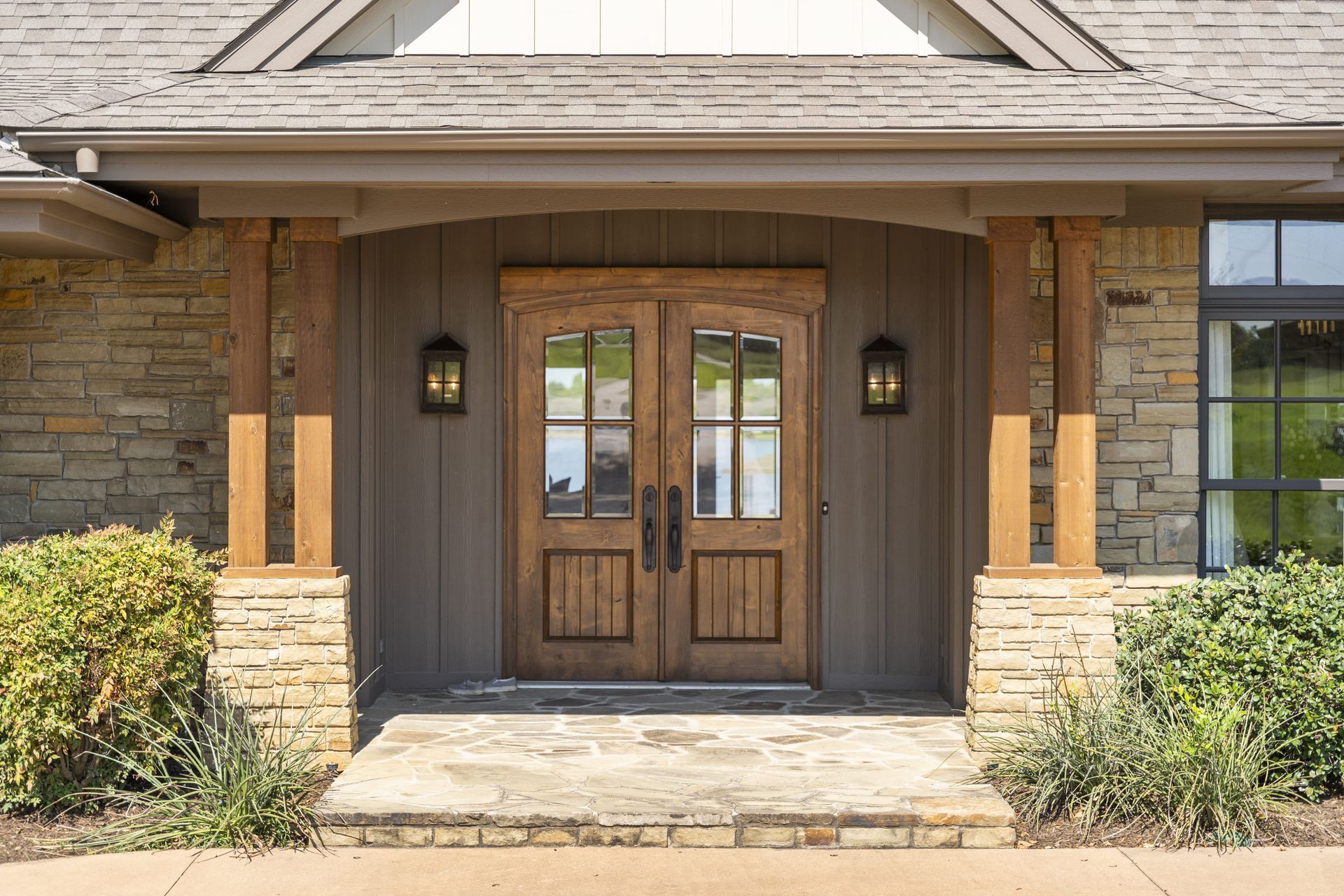 The front door of a house with a wooden door and a stone porch.