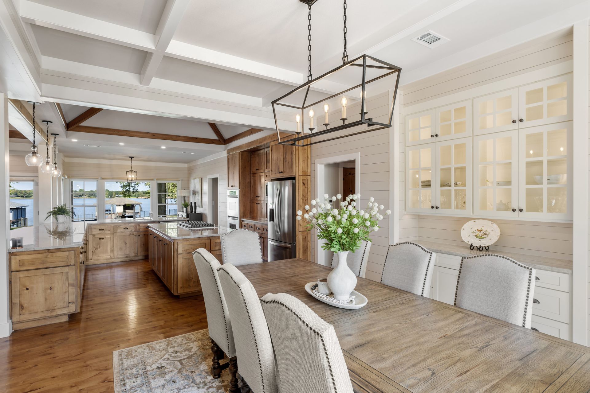 A dining room table and chairs in a kitchen with a vase of flowers on it.