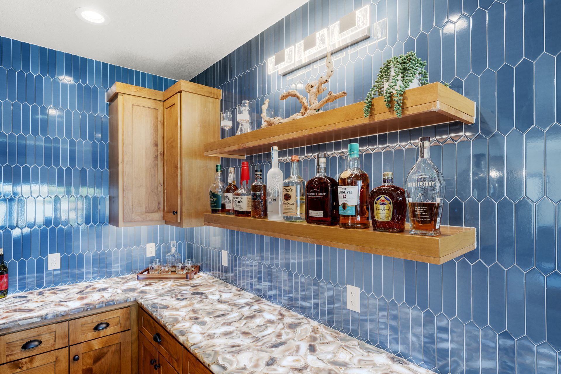 There are many bottles of alcohol on the shelves in the kitchen.