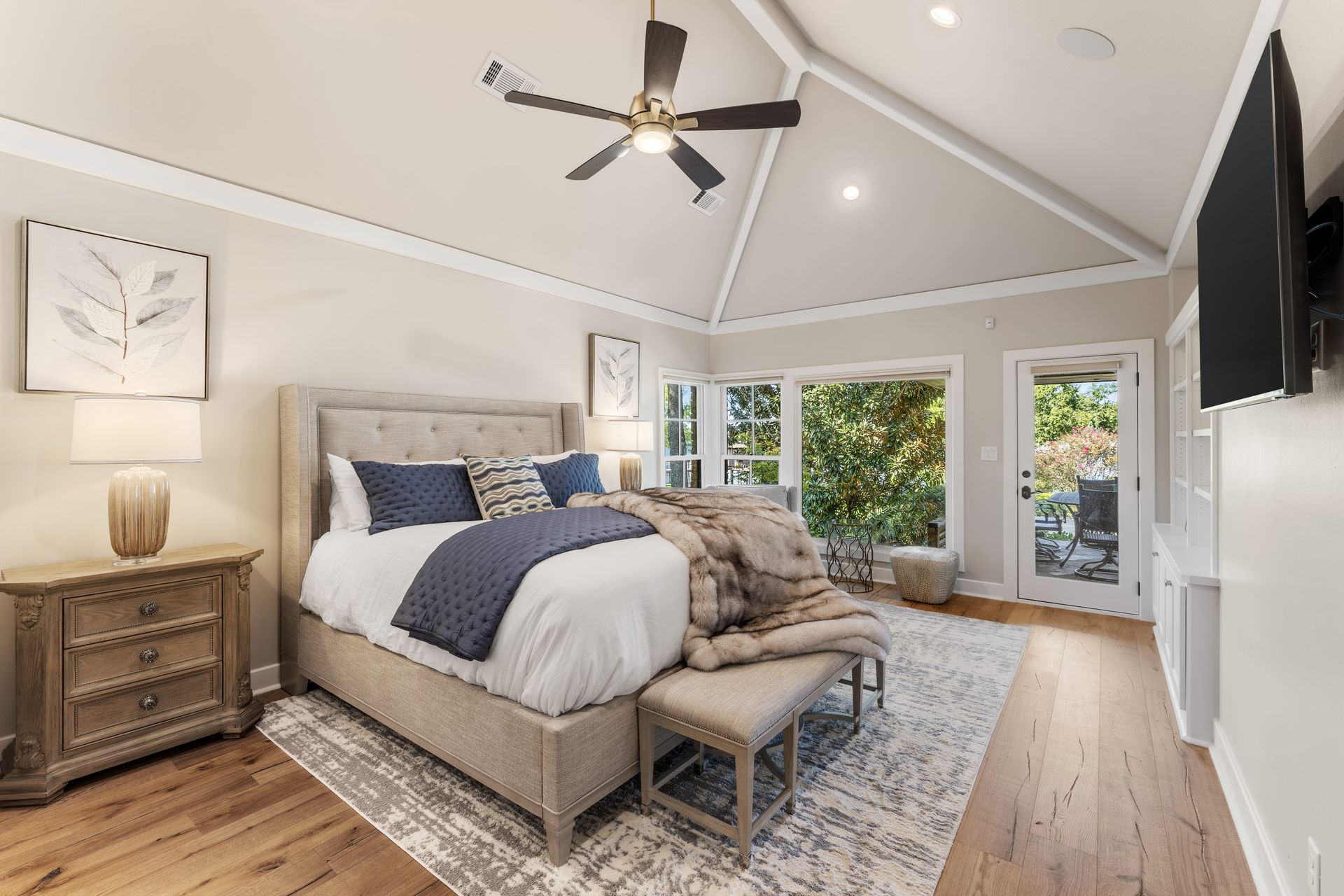 A bedroom with a bed , nightstand , television and ceiling fan.