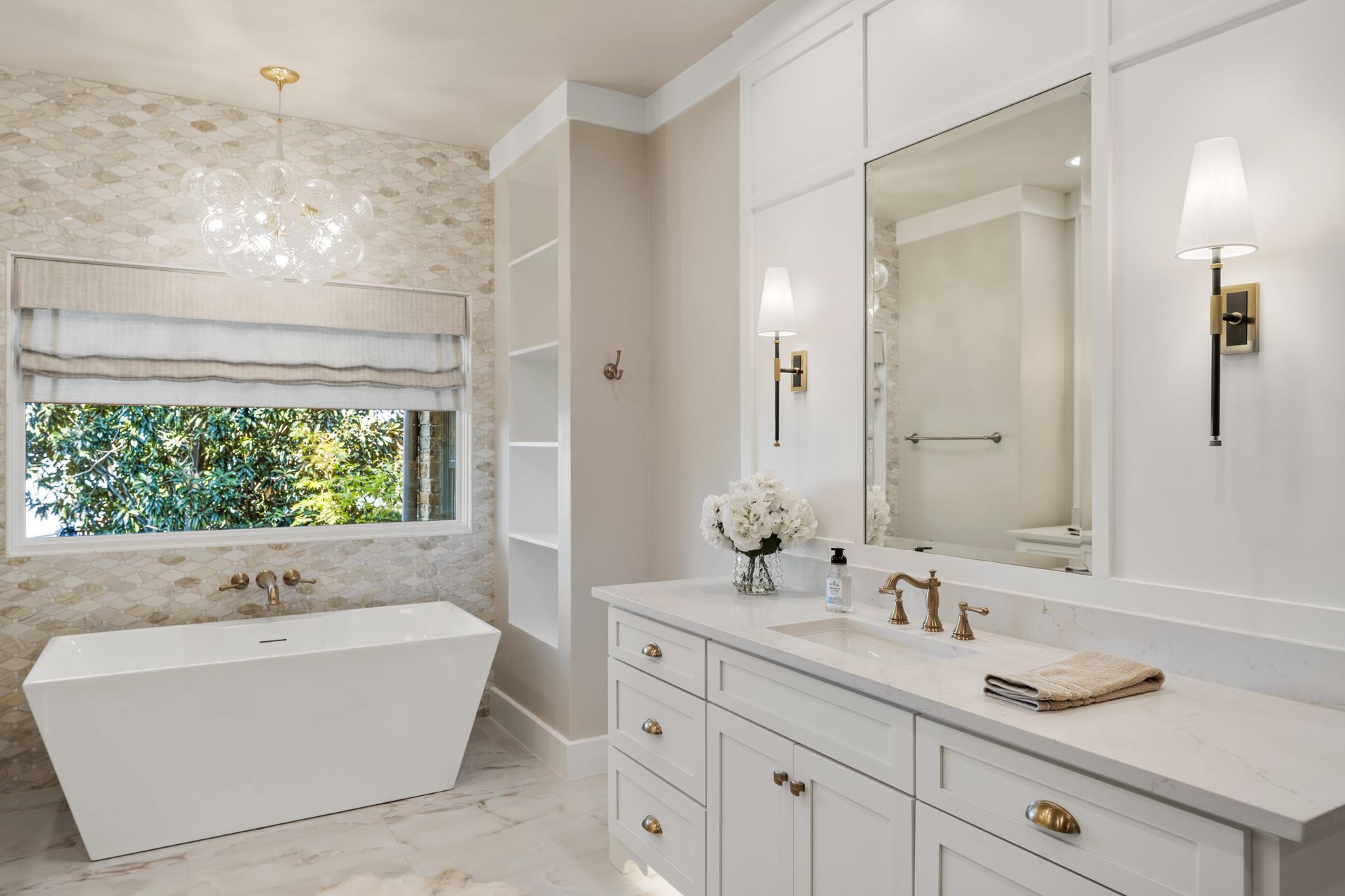 A bathroom with a tub , sink , mirror and window.