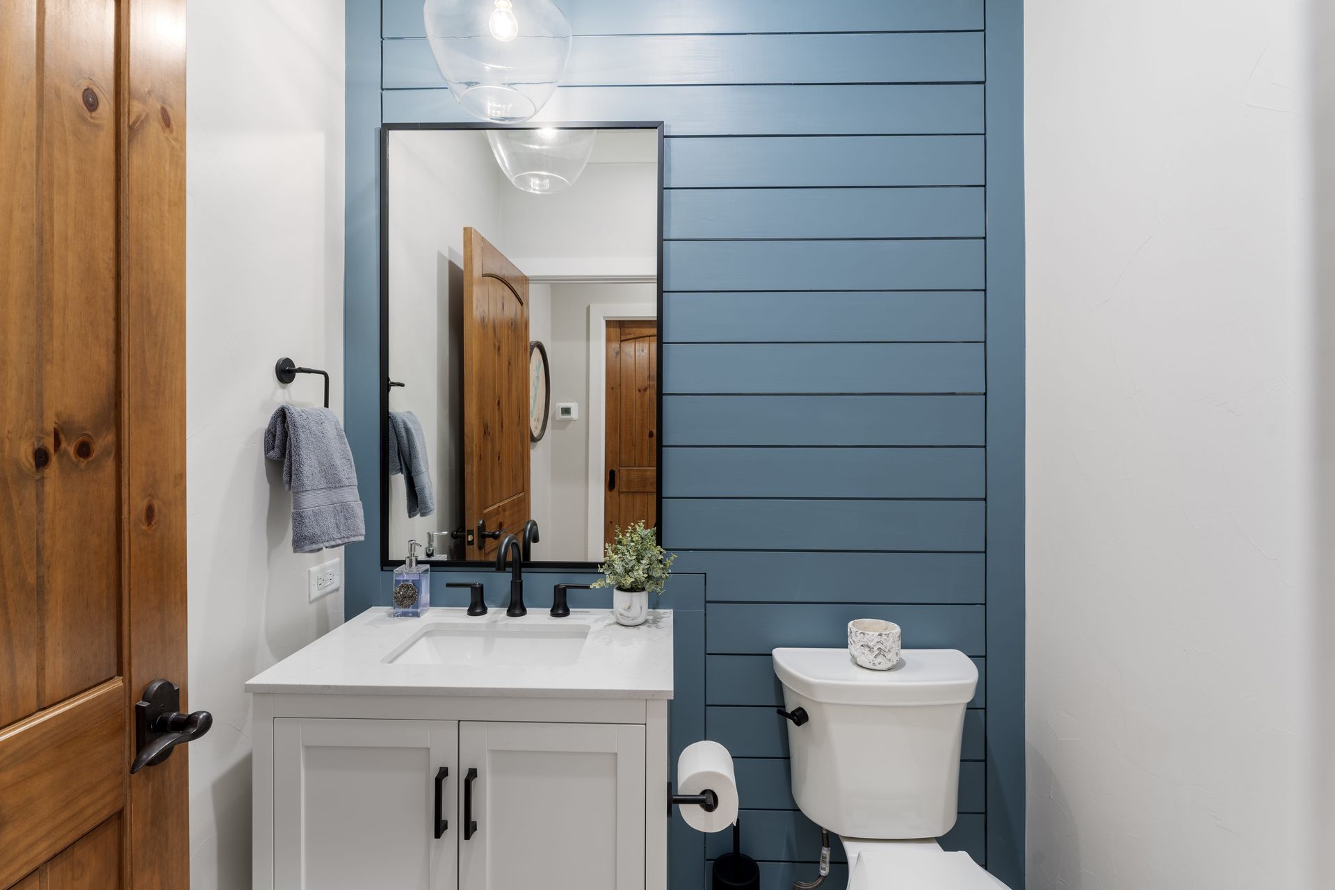 A bathroom with a sink , toilet , mirror and blue wall.