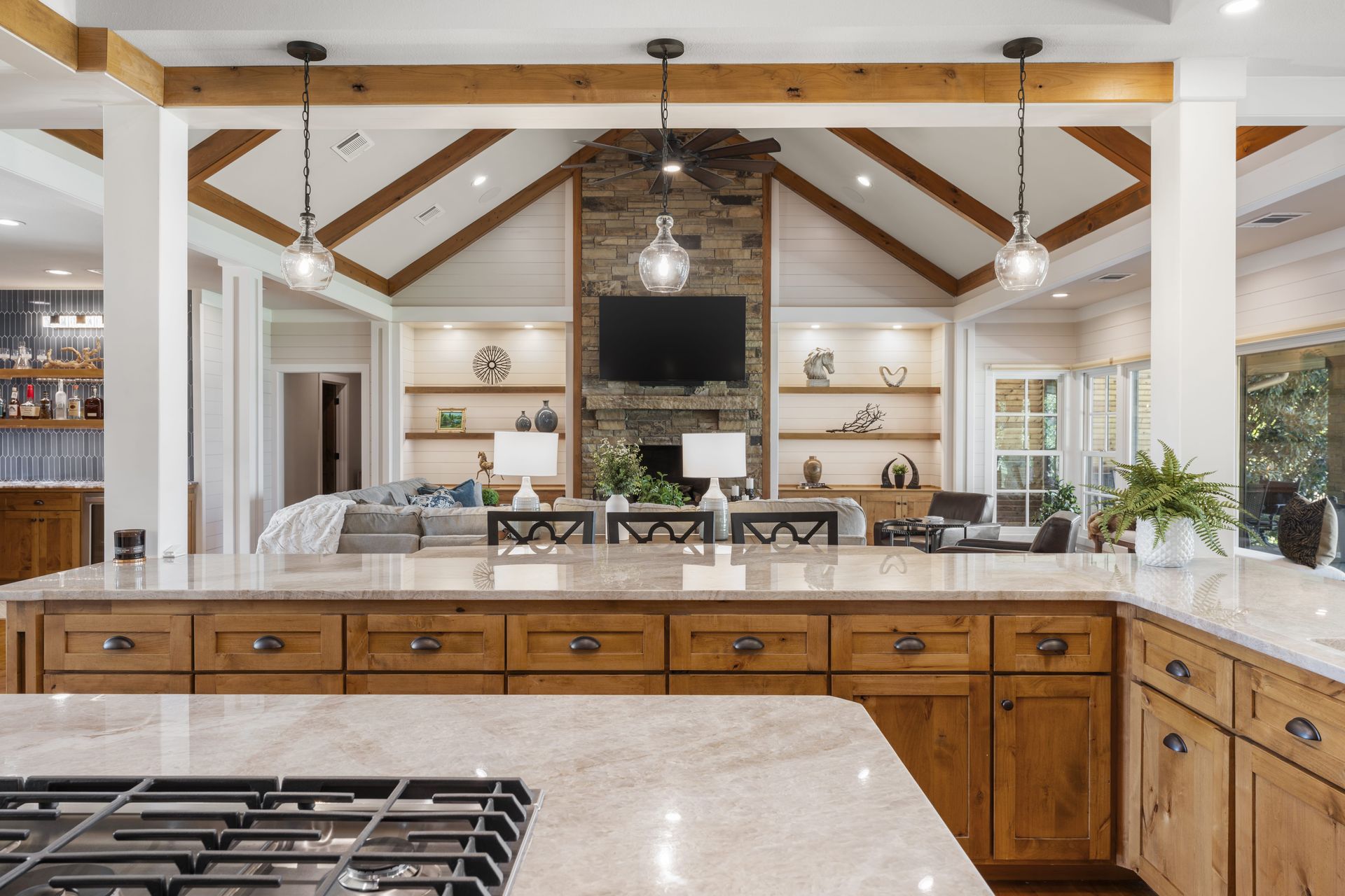 A kitchen with wooden cabinets , granite counter tops , a stove and a television.