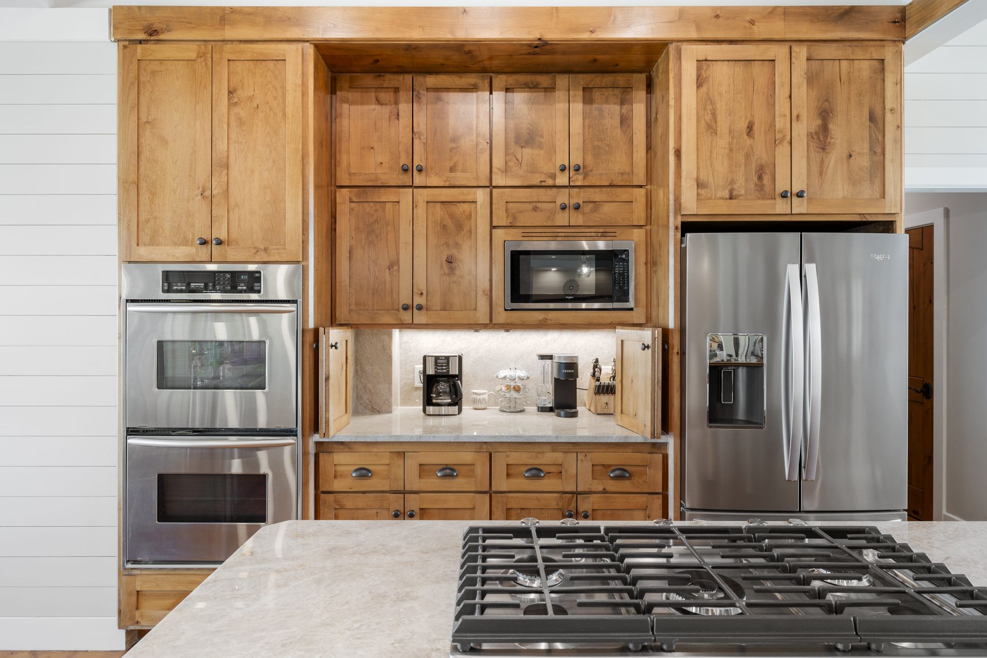 A kitchen with wooden cabinets , stainless steel appliances and a stove top oven.