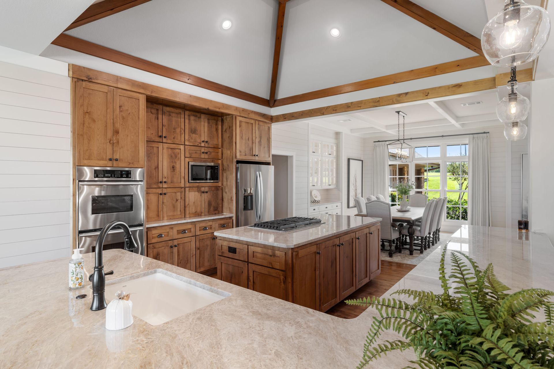 A kitchen with wooden cabinets , stainless steel appliances , a sink , and a large island.