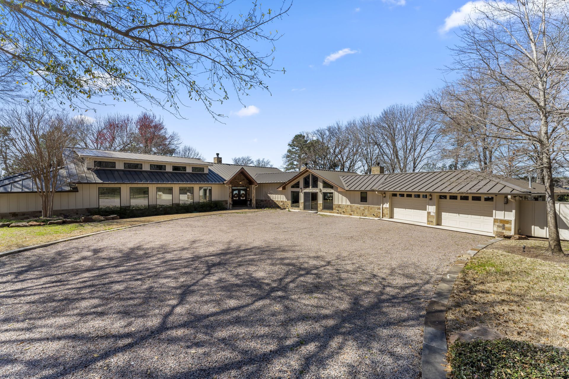 A large house with a gravel driveway and trees in front of it.