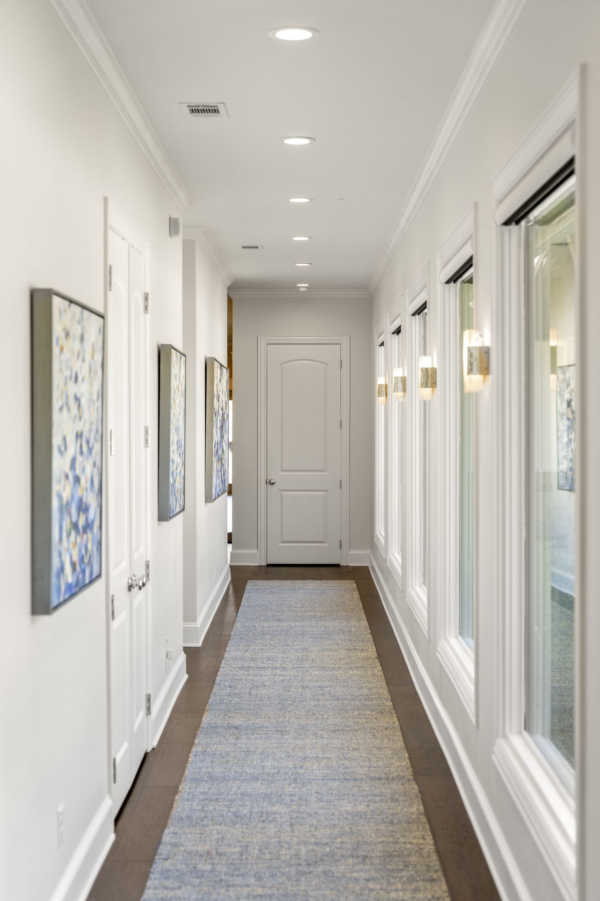 A long hallway with white walls and a rug on the floor.