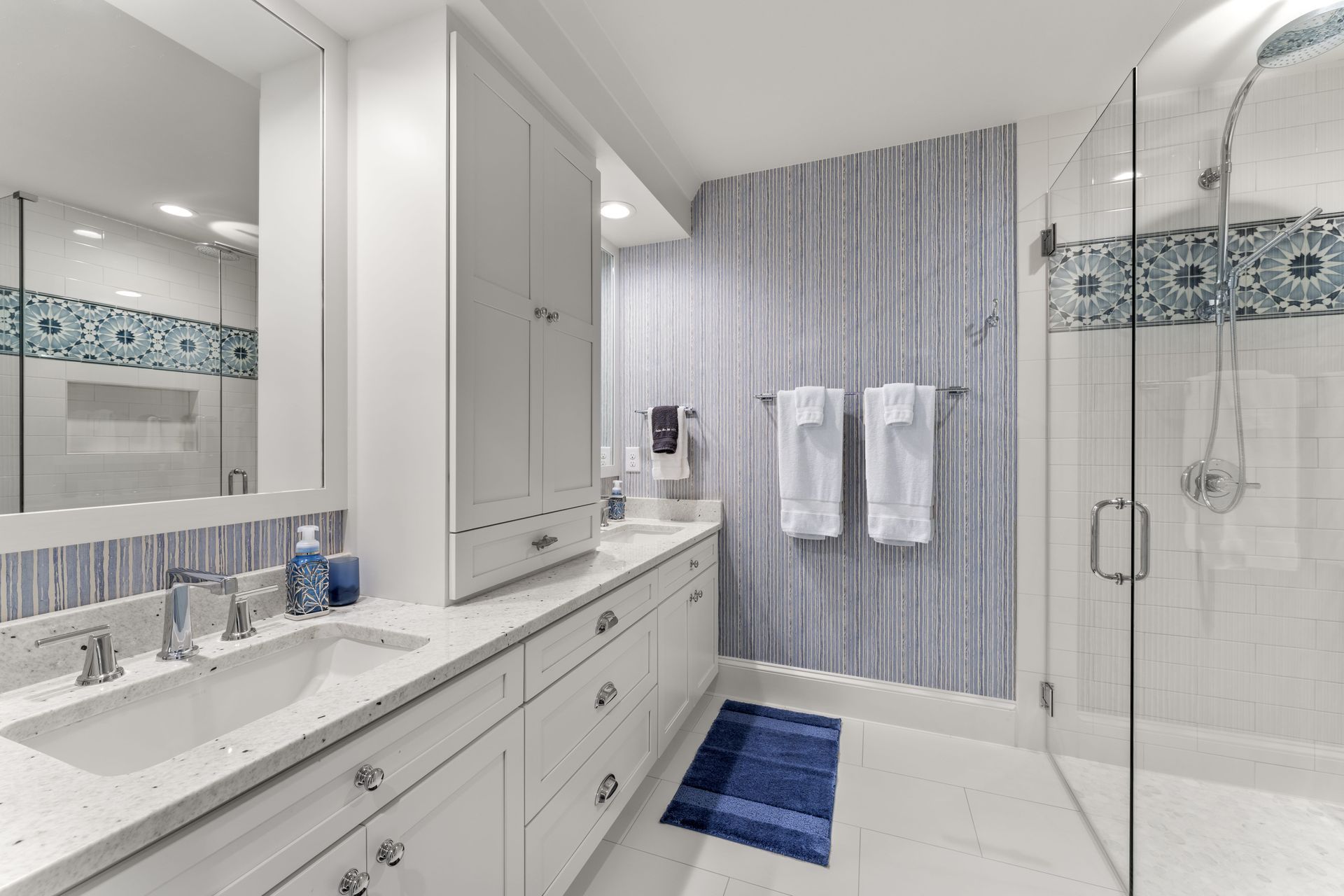 A bathroom with two sinks and a walk in shower.