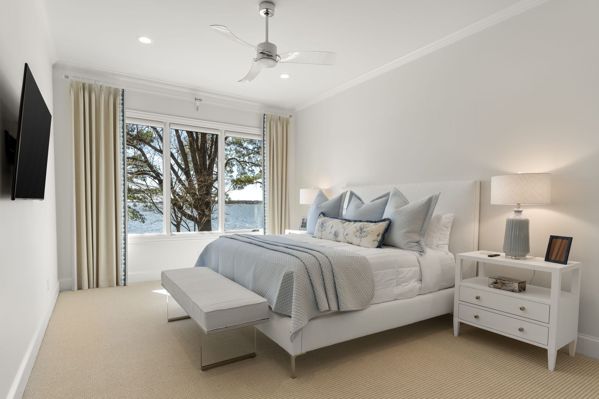 A bedroom with a king size bed , nightstands , lamps and a television.