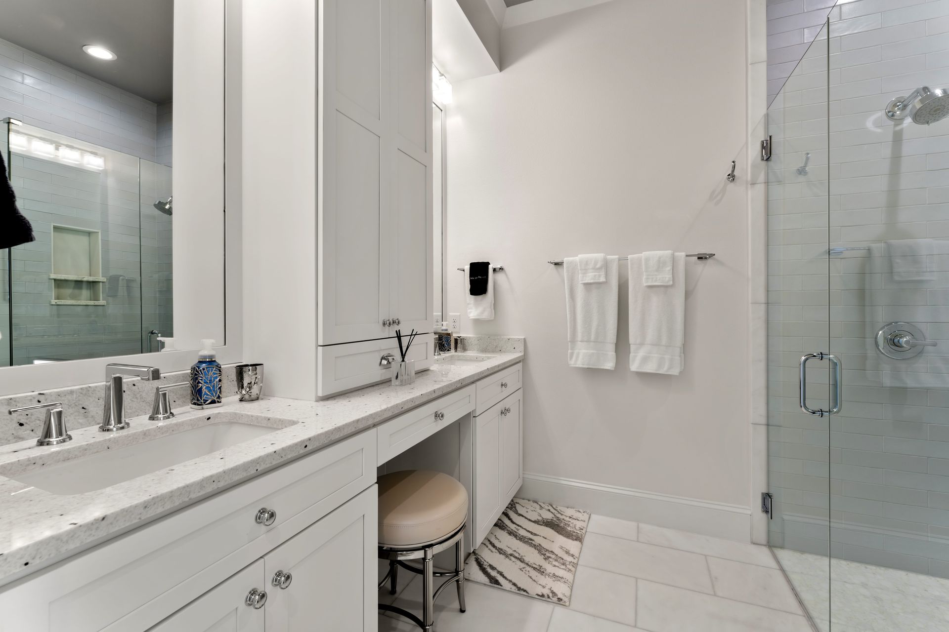 A bathroom with a sink , mirror and walk in shower.