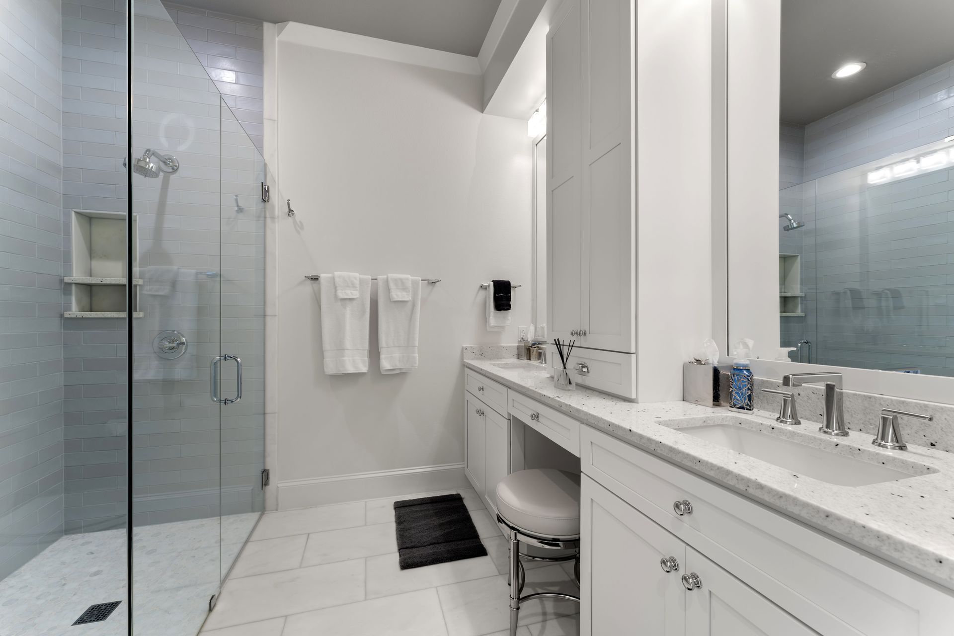A bathroom with two sinks , a walk in shower and a mirror.