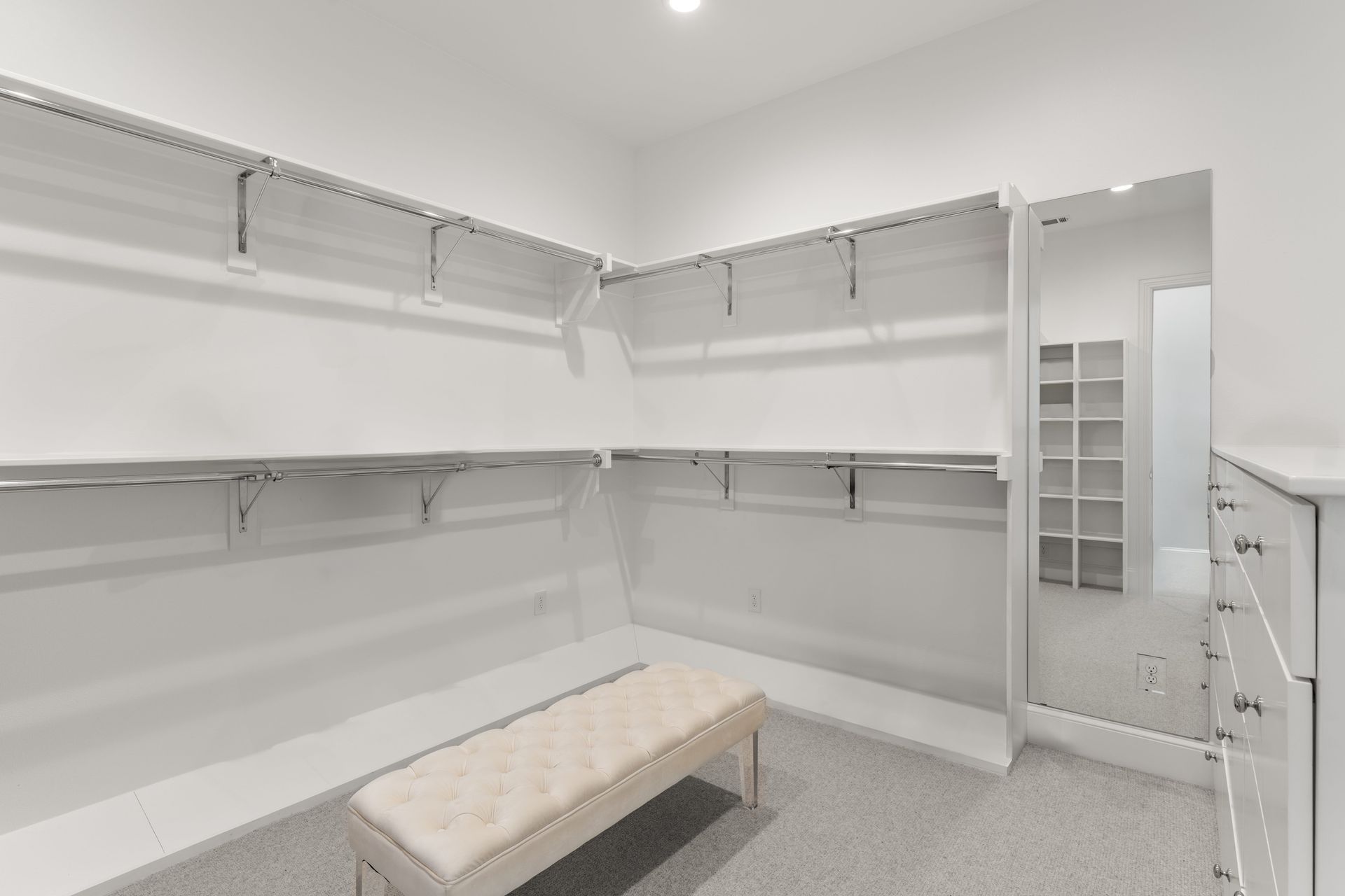 A walk in closet with lots of shelves and a bench.