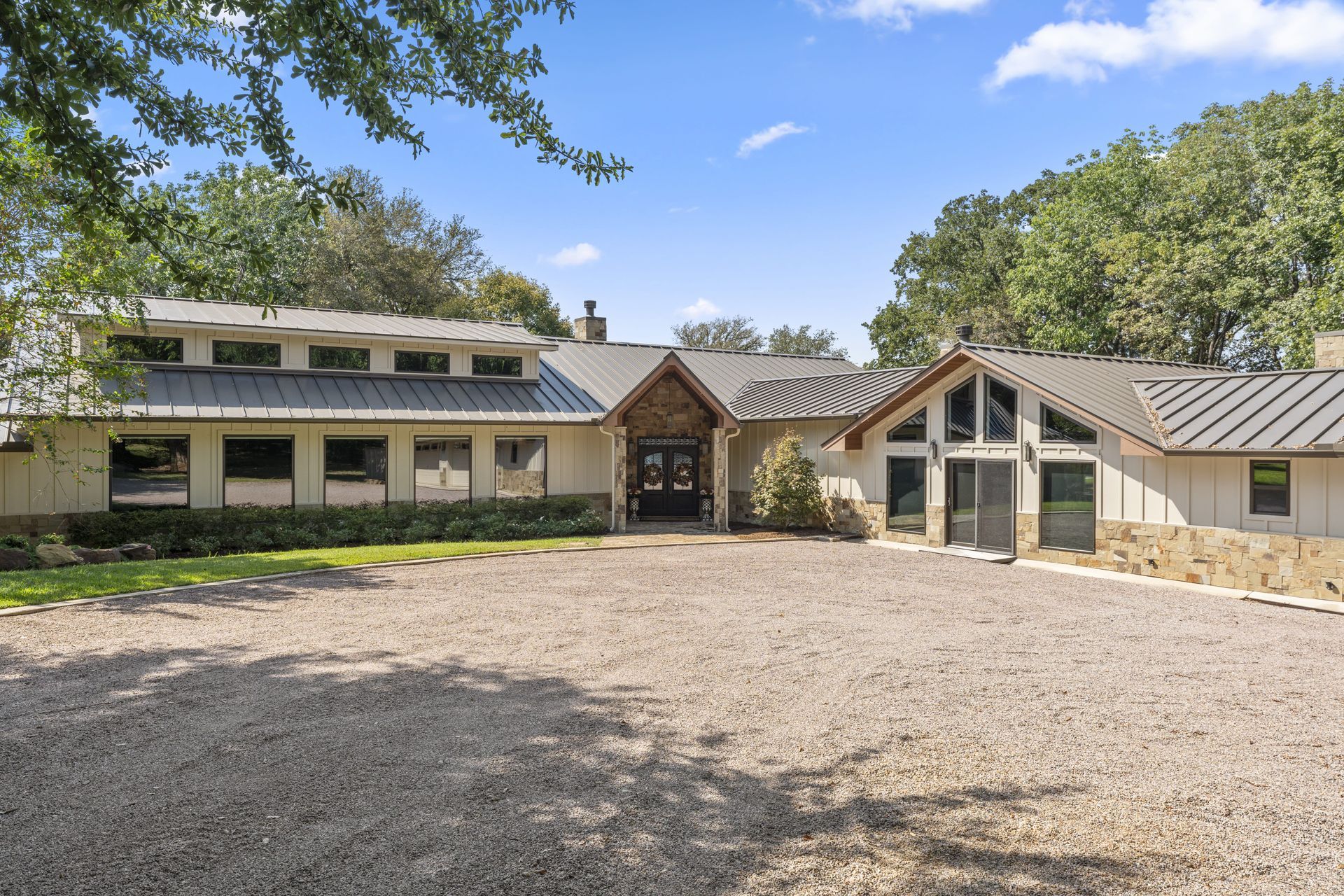 A large white house with a gravel driveway in front of it.