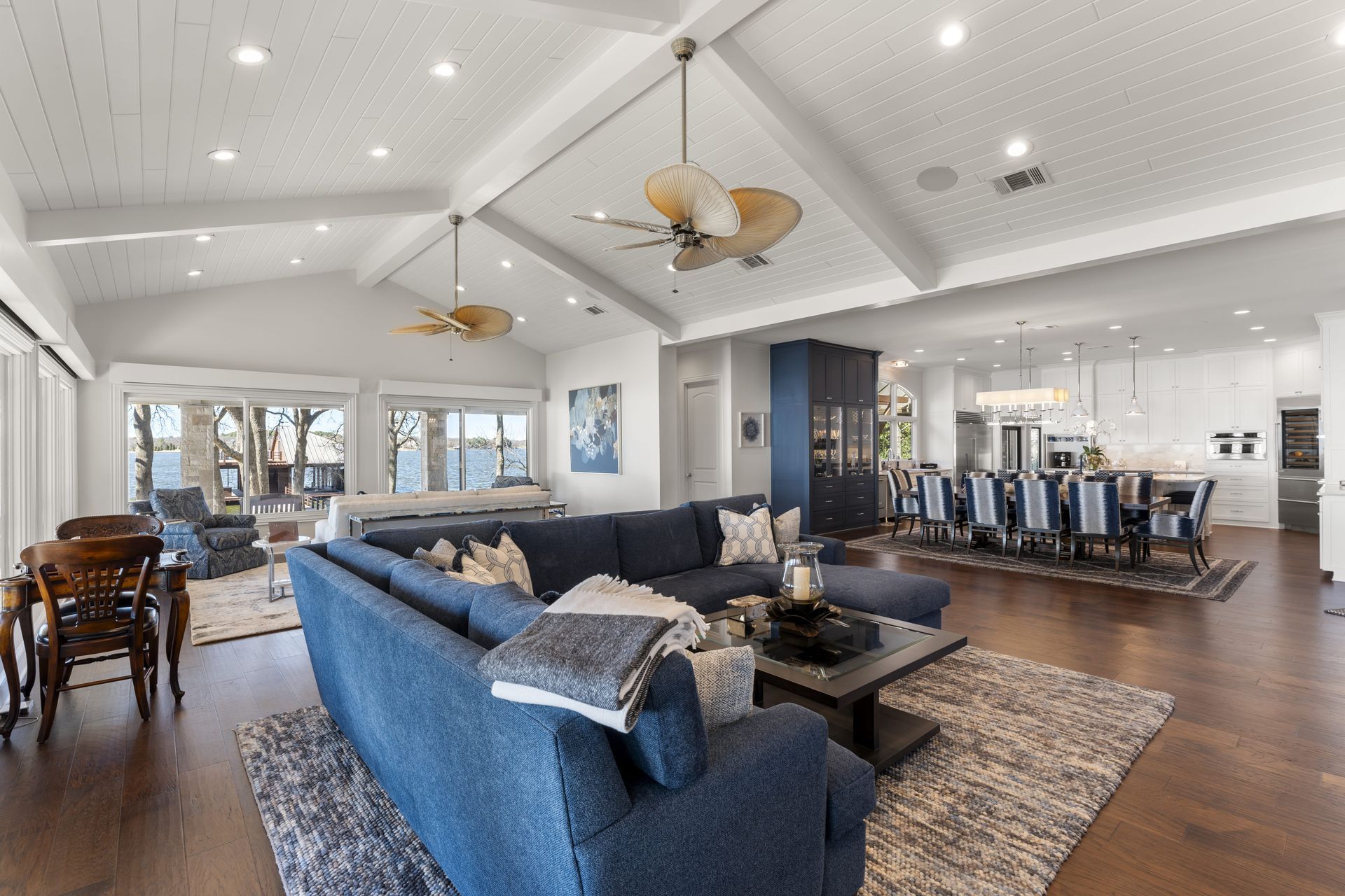 A living room with a blue sectional couch and a ceiling fan.