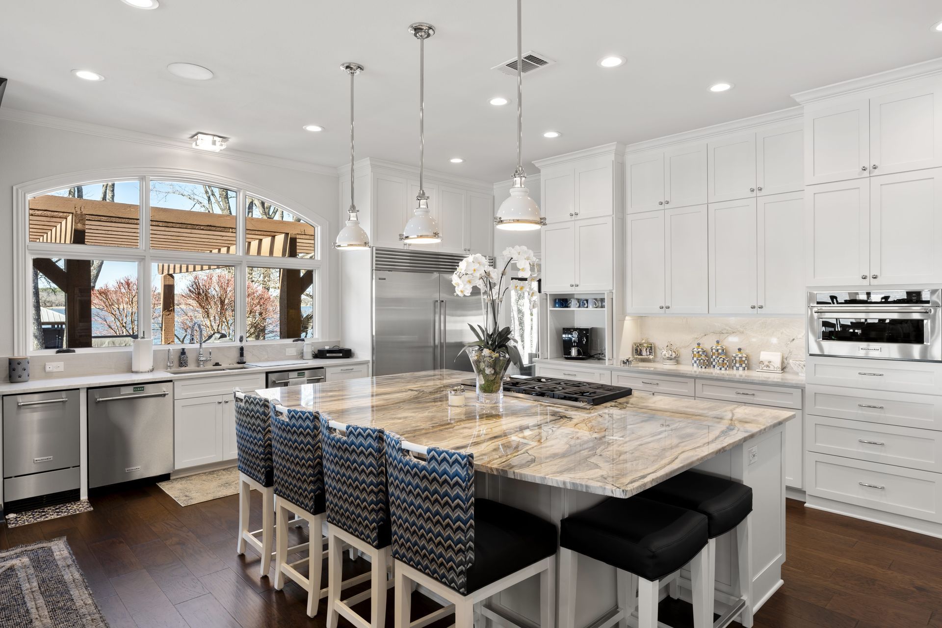 A kitchen with white cabinets , granite counter tops , stainless steel appliances , and a large island.