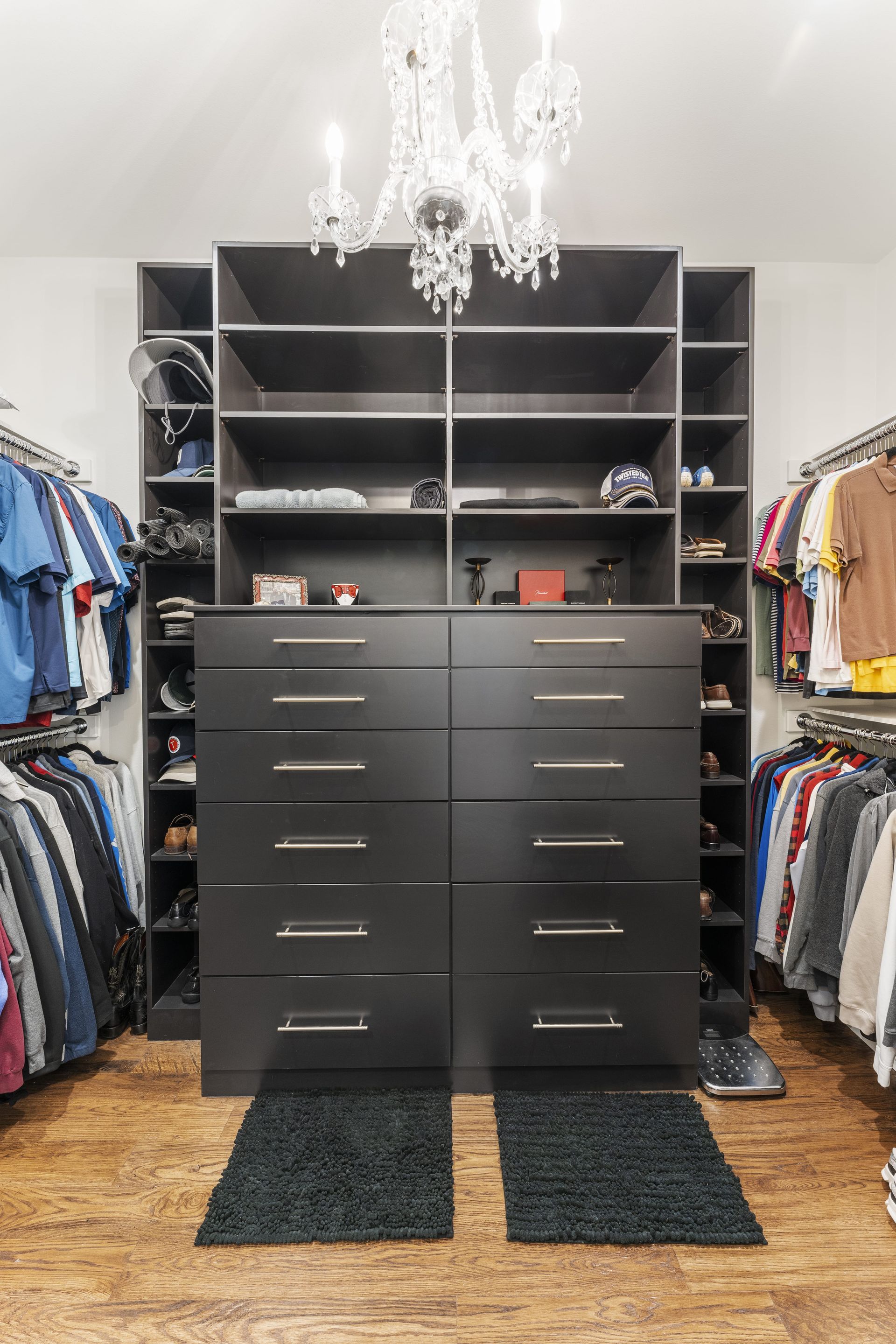 A walk in closet filled with lots of clothes and a chandelier.