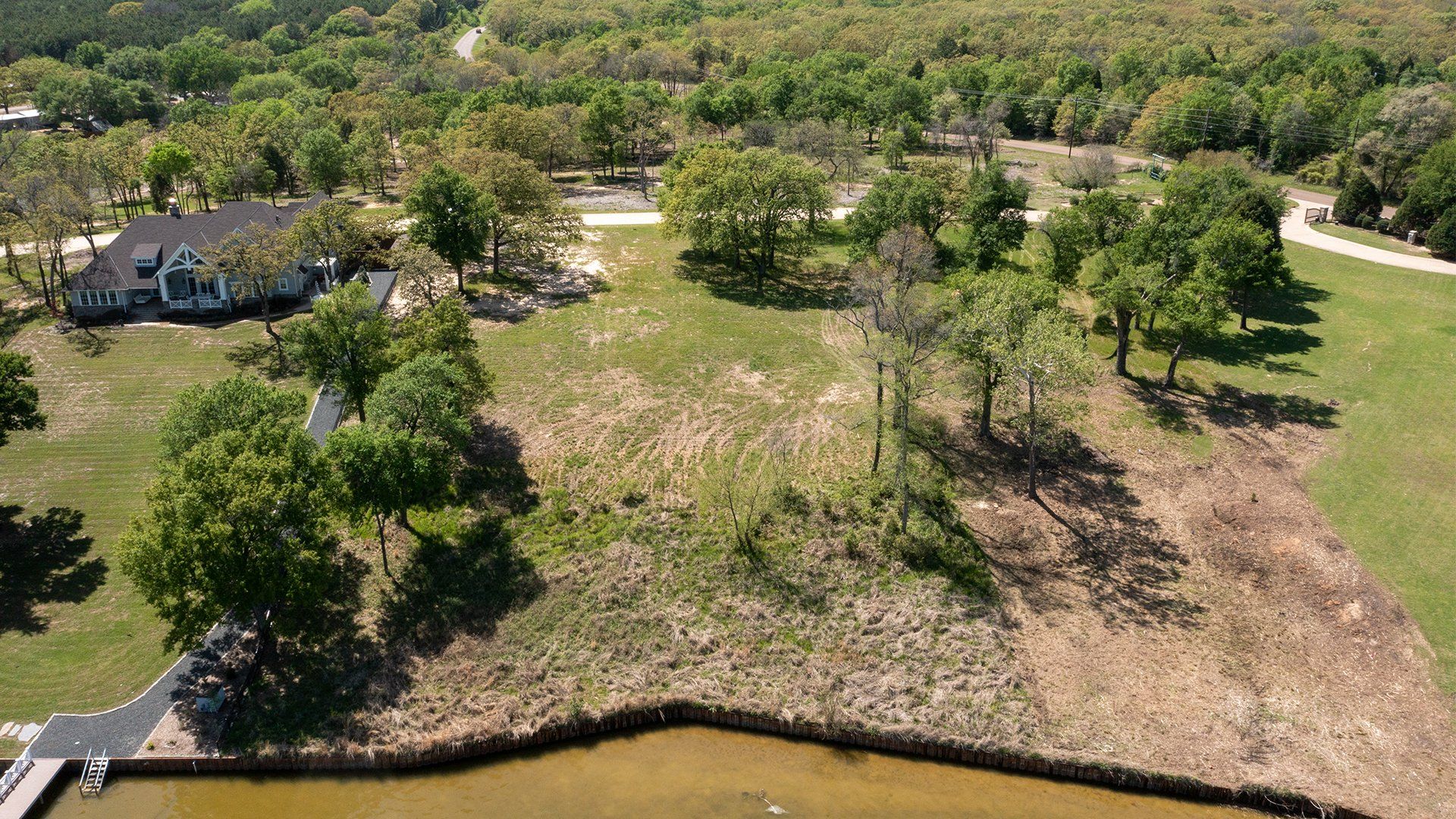 An aerial view of a house surrounded by trees and a lake.