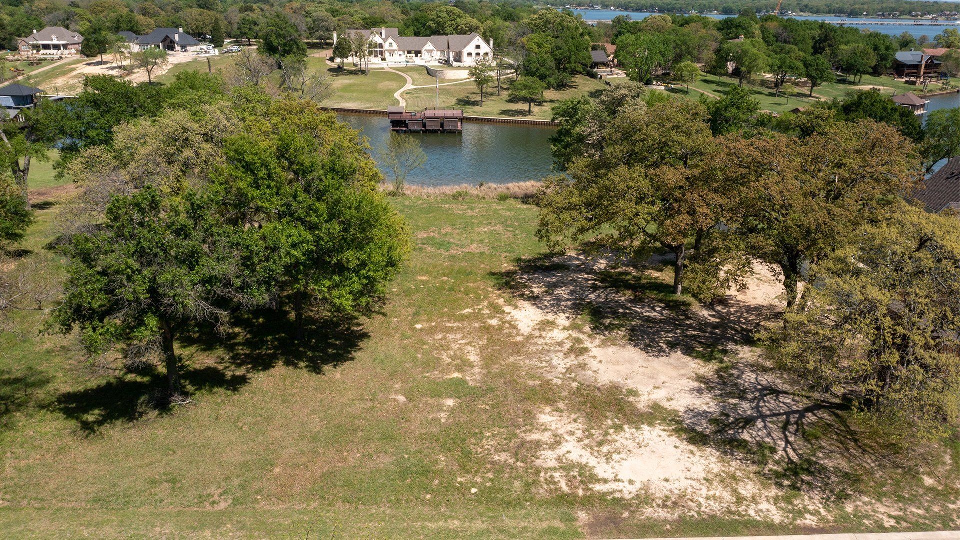 An aerial view of a residential area with trees and a lake in the background.