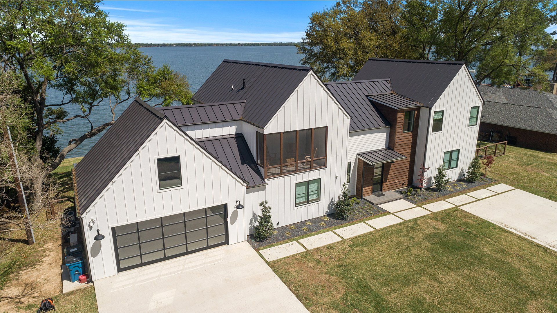 An aerial view of a large white house with a black roof next to a body of water.