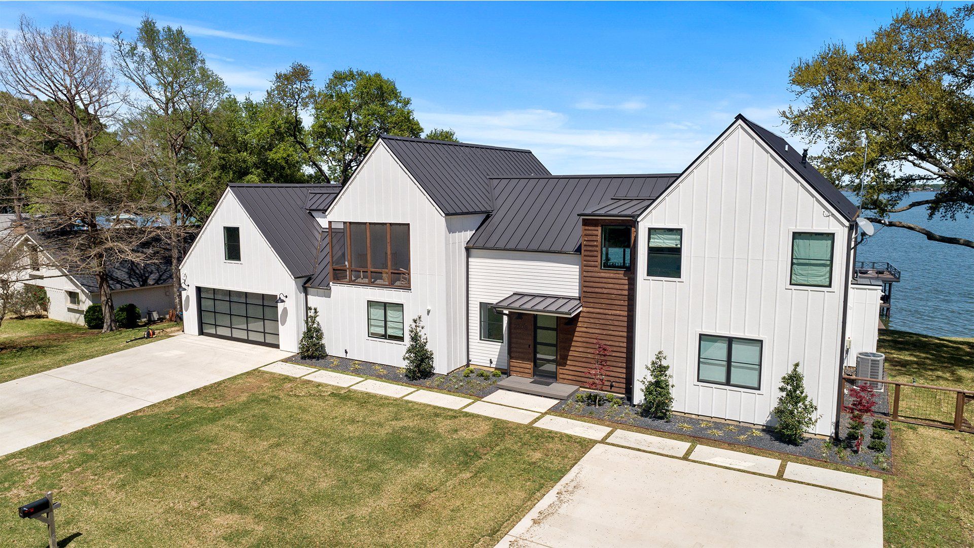 A large white house with a black roof is sitting next to a body of water.