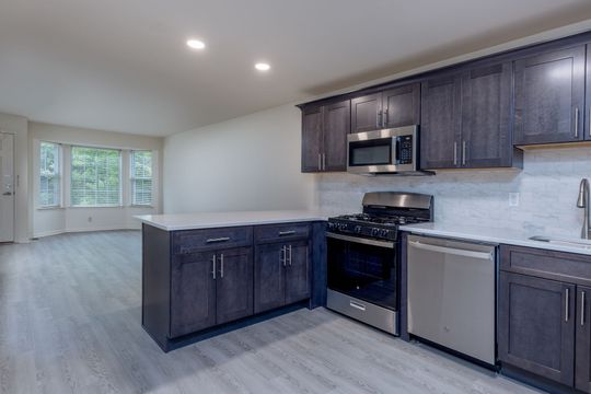 An empty kitchen with stainless steel appliances and gray cabinets.