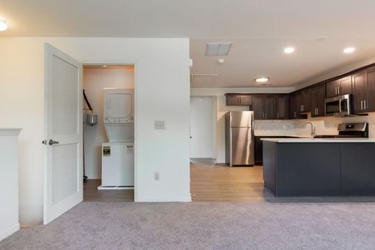 A kitchen with stainless steel appliances and a laundry room with a washer and dryer.