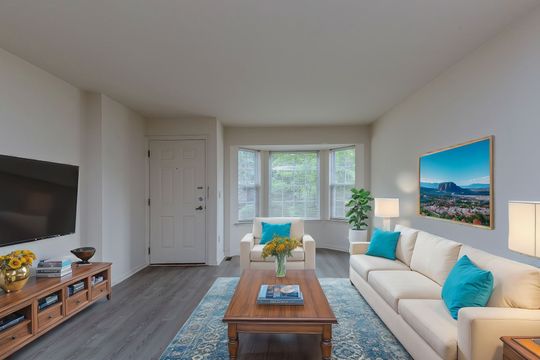 A living room with a couch , chair , coffee table and television.