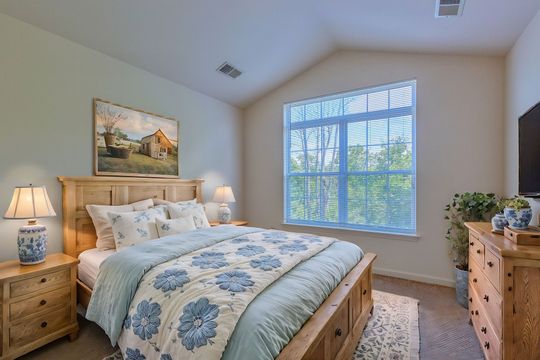 A bedroom with a bed , dresser , nightstand and television.