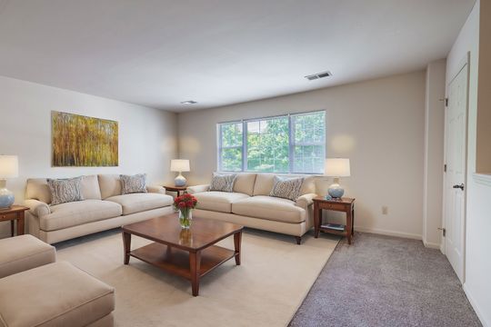 A living room with two couches , a coffee table , and a painting on the wall.