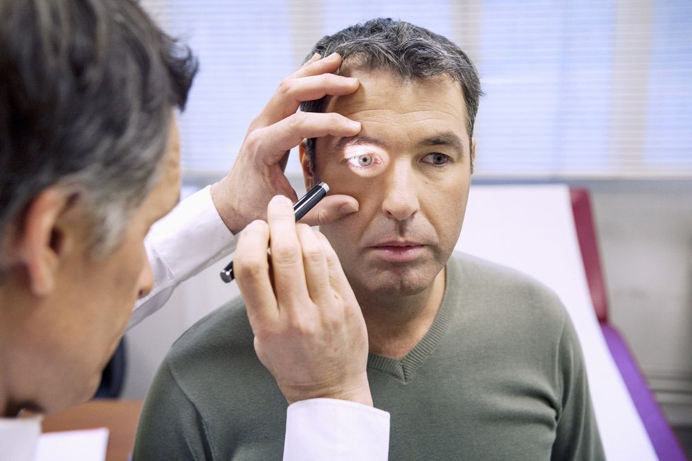 A Doctor is Examining a Man's Eye With a Magnifying Glass — Mount Archer Medical Centre in Berserker, QLD