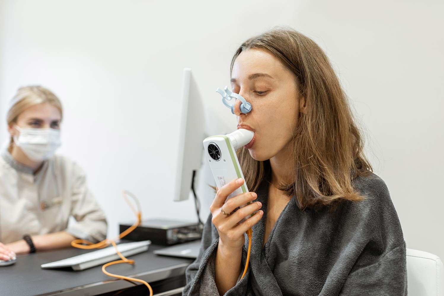 A Woman is Wearing a Mask While Using an Inhaler — Mount Archer Medical Centre in Berserker, QLD