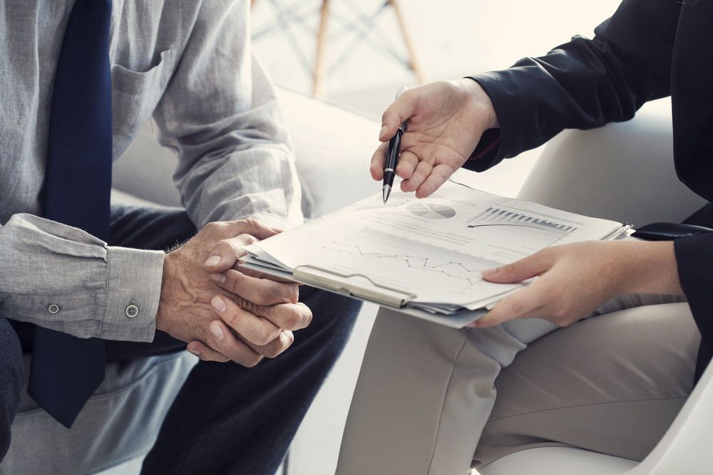 A Man and a Woman Are Sitting on a Couch Looking at a Clipboard — Mount Archer Medical Centre in Berserker, QLD