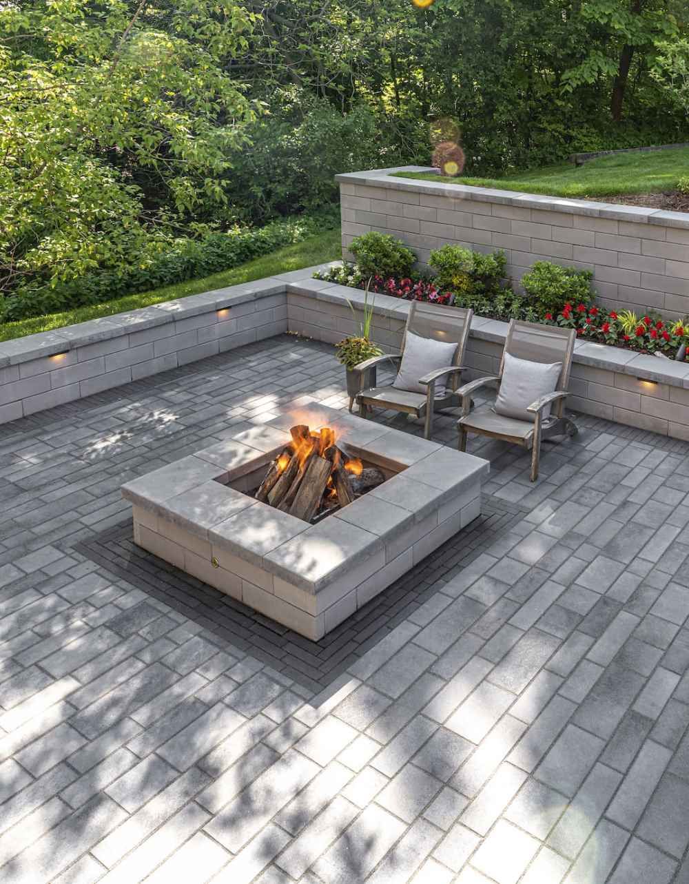 A stone path winds through a lush garden with manicured shrubs, a rock feature, and a vibrant green lawn.