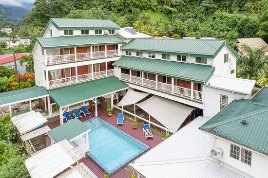 Hotel with a green roof and a pool in a tropical setting.