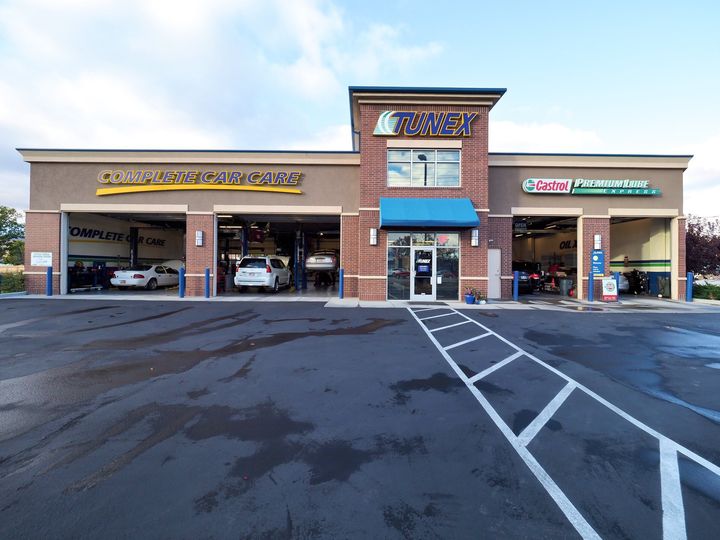 A car dealership with cars parked in the garage and a parking lot in front of it.