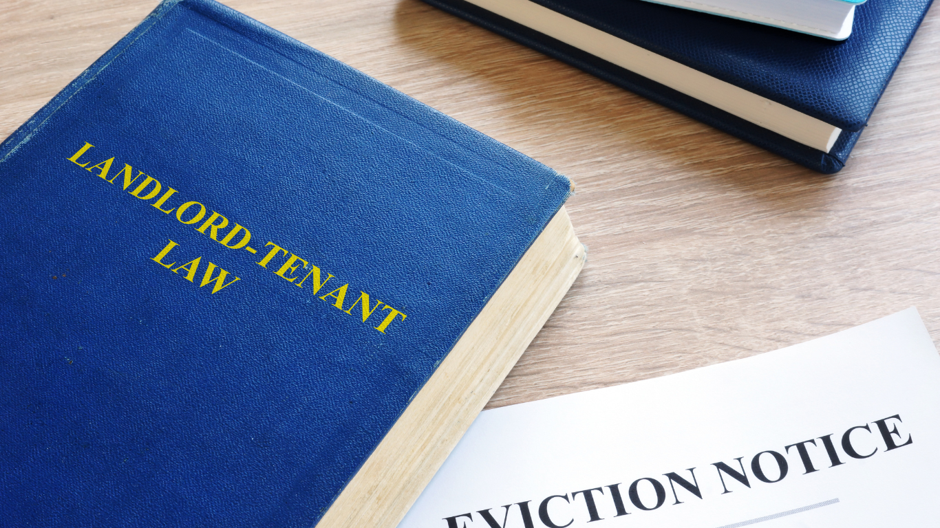 A wooden gavel is sitting on top of a book titled landlord-tenant law.