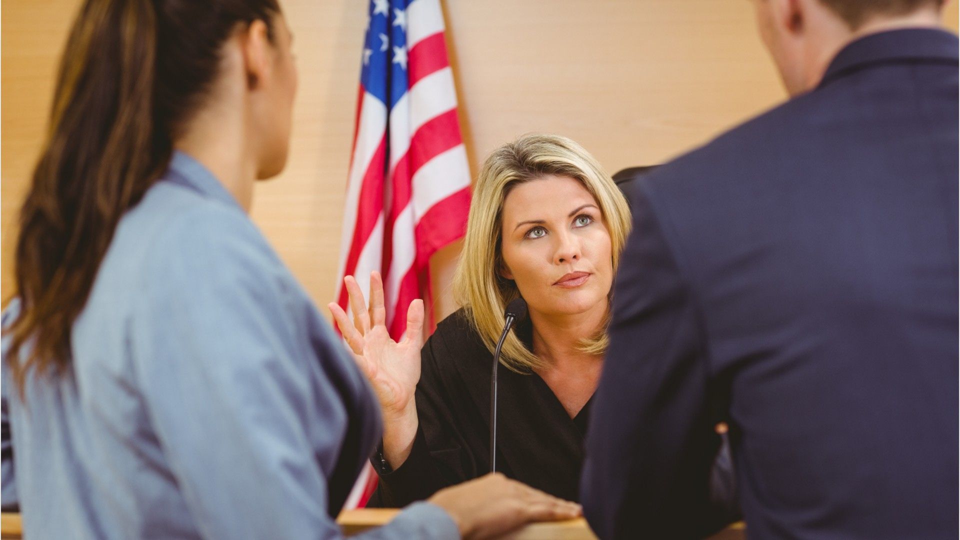 A judge is talking to a couple of people in a courtroom.