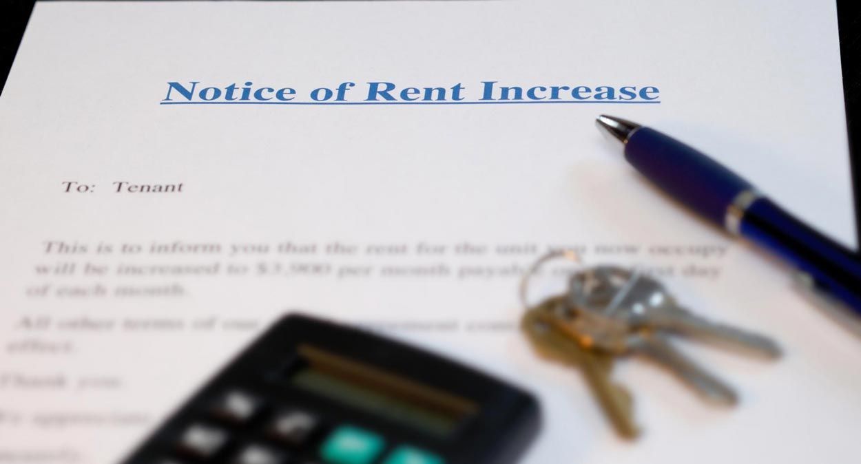 A notice of rent increase with keys and a pen