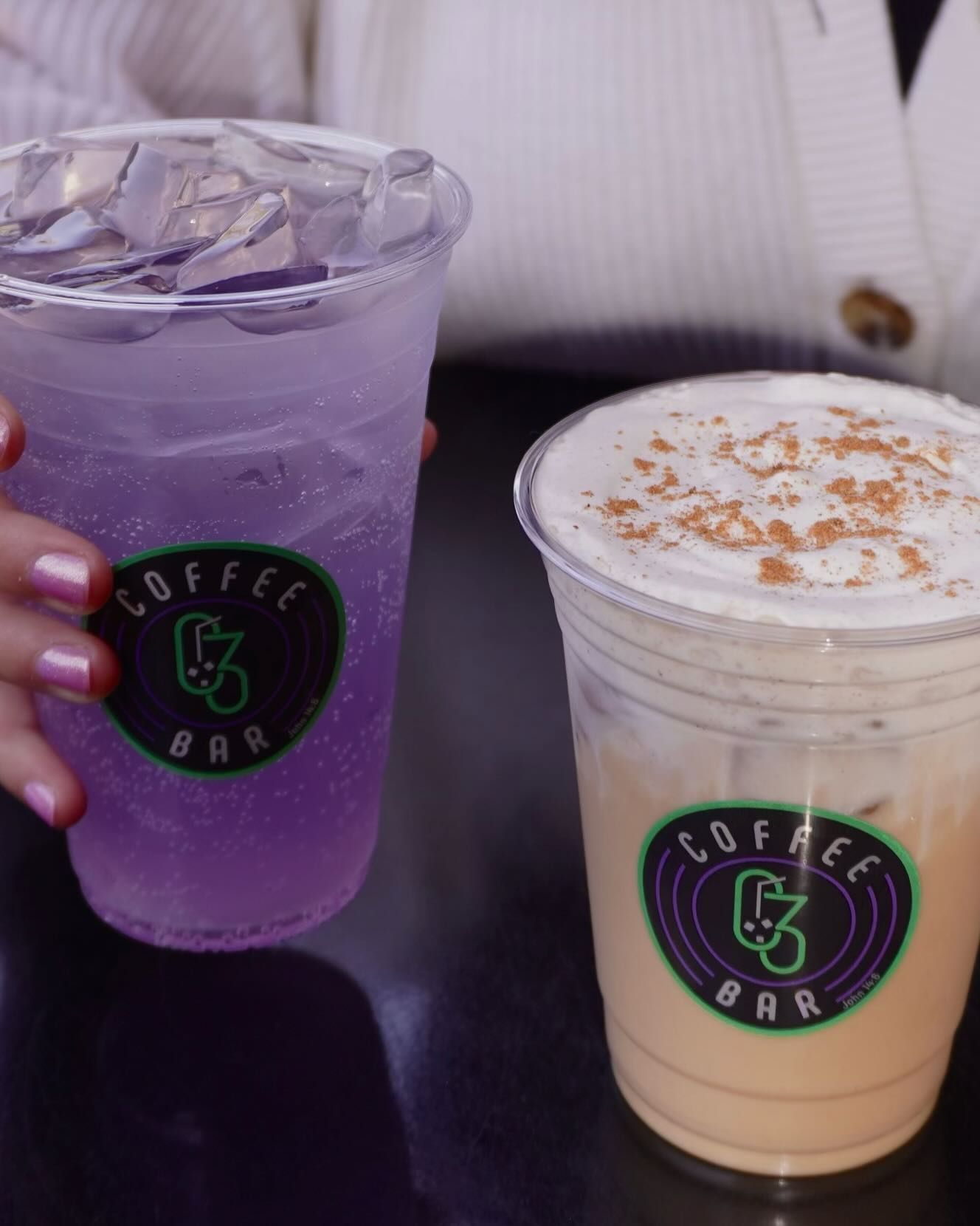 Two iced drinks from a Coffee Bar: purple soda and a latte with cinnamon on top.