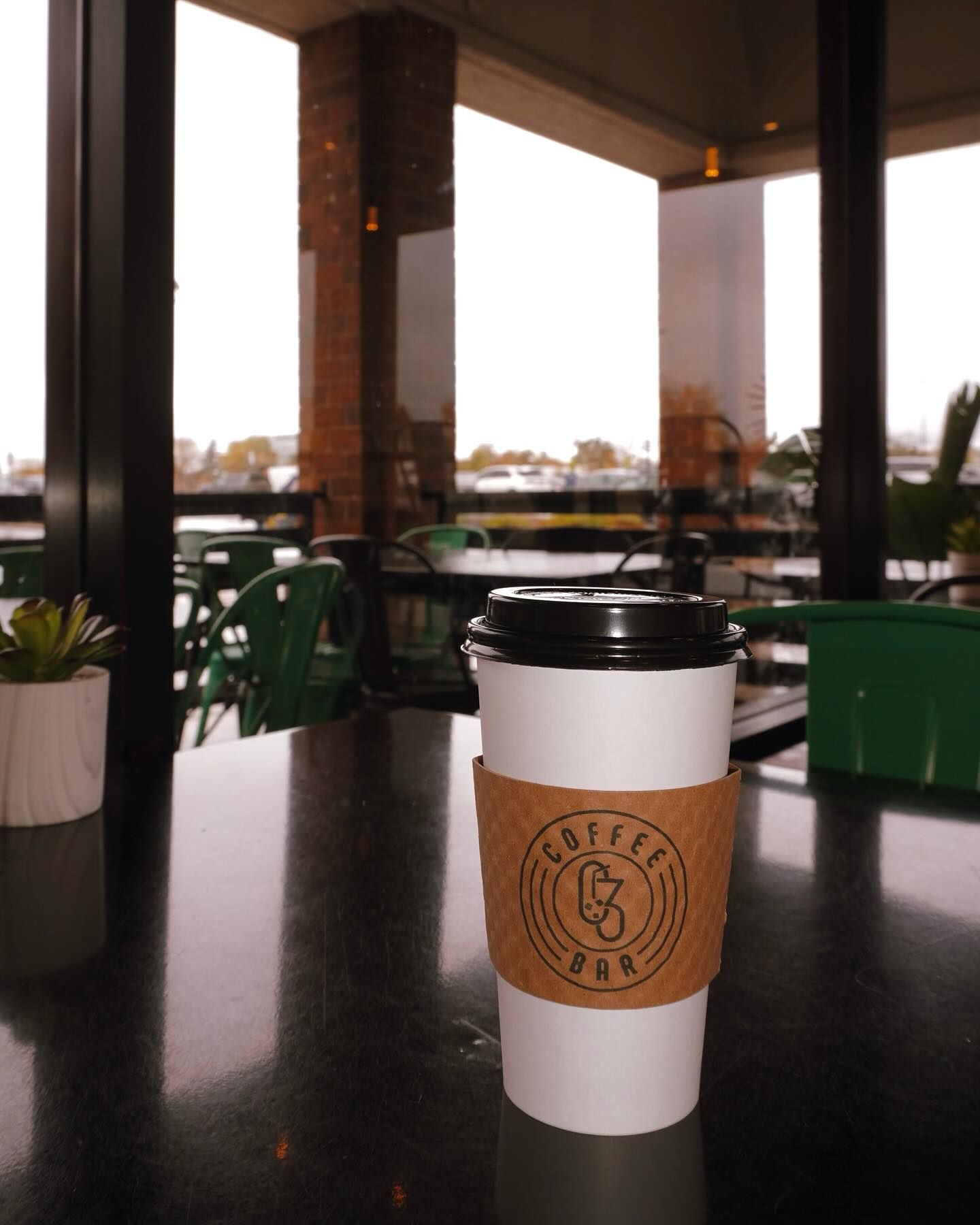 Coffee cup on a table in a cafe, with a natural light outside.